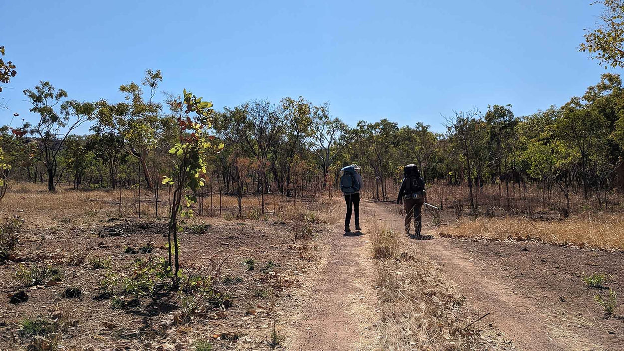 two hikers walking on red dry dirt in full sun